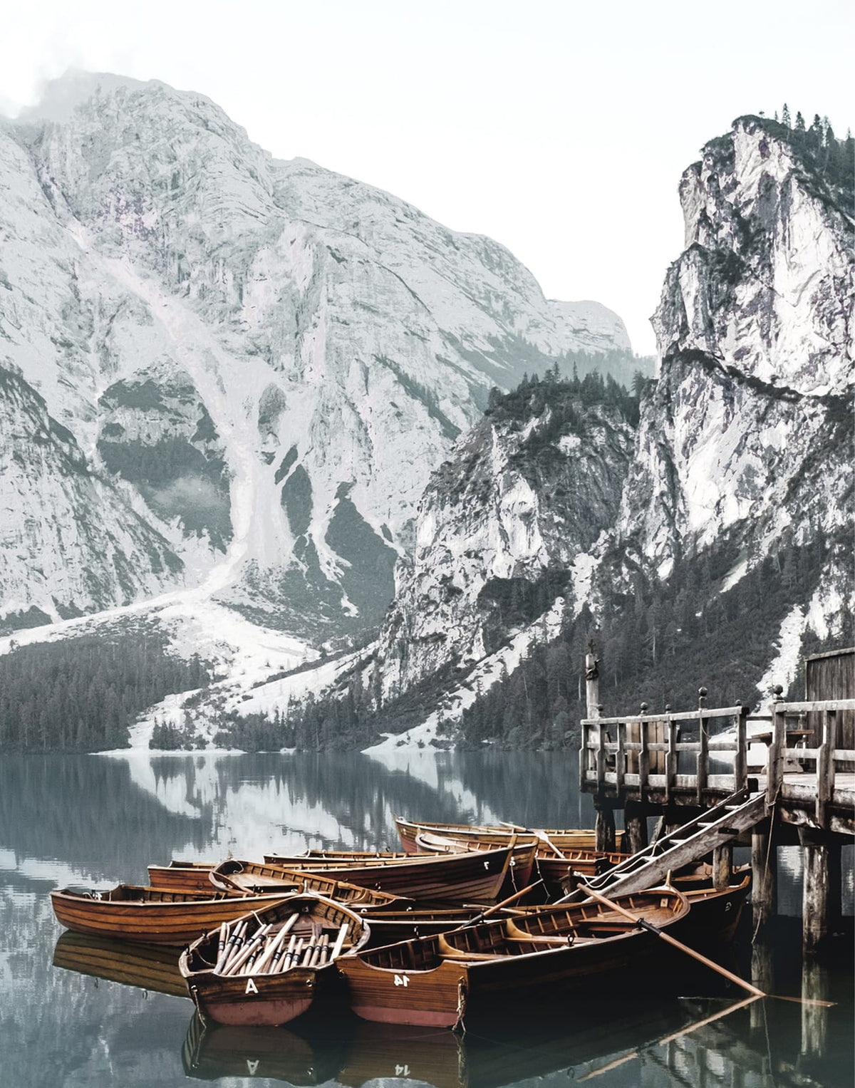 Boat on cool blue-gray water below rugged mountain slopes