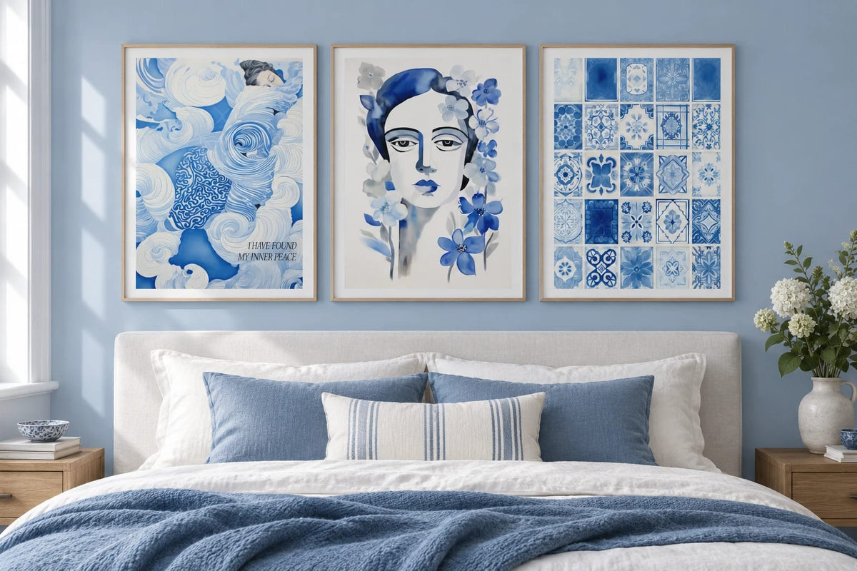 Blue wave, floral portrait, and tile prints hang above a bed in a blue bedroom.