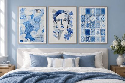 Blue wave, floral portrait, and tile prints hang above a bed in a blue bedroom.