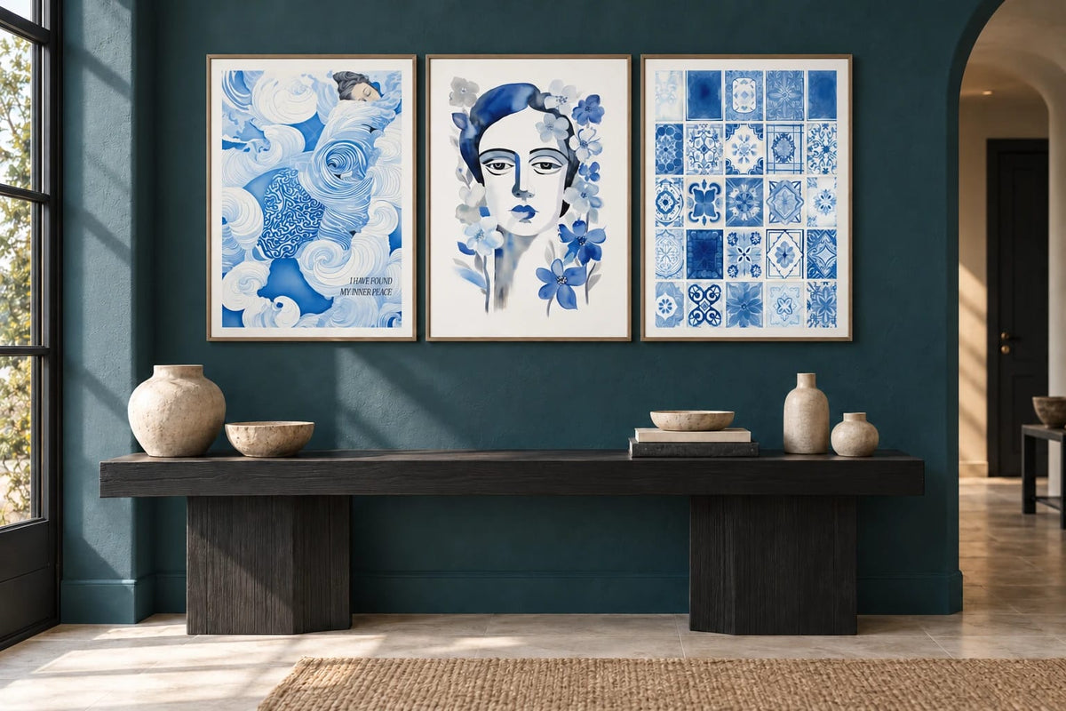 Blue wave, portrait, and tile prints hang on a green wall above a dark wood console.