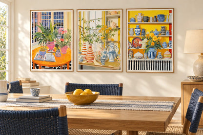 Plant and blue-white ceramic prints appear in a light dining room with a wooden table.
