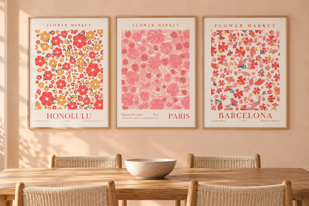 Floral triptych in light wood frames above a dining table with woven chairs.