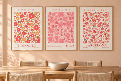Floral triptych in light wood frames above a dining table with woven chairs.