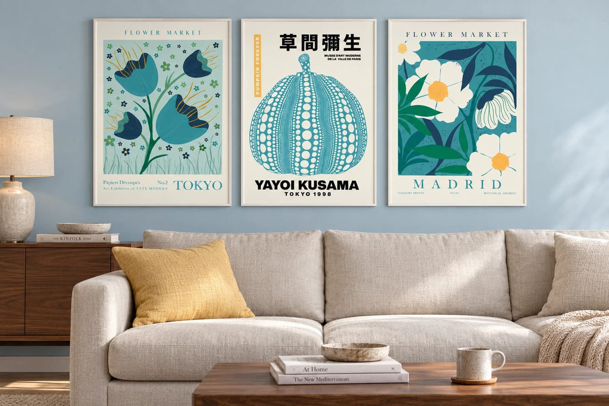 Flower and pumpkin prints above a light sofa on a blue wall.