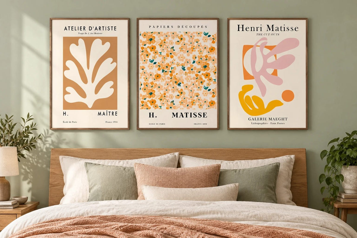 Cut-out style botanical prints above a bed against sage.