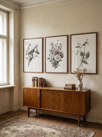 Three flower prints grouped above a wooden dresser.