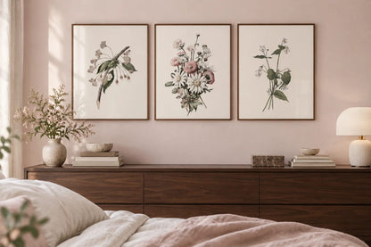 A floral print trio above a dark dresser on a soft pink wall.