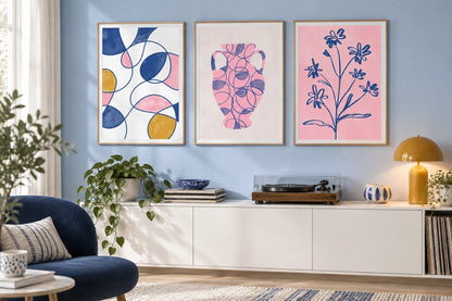 Blue and pink prints grouped above a white console.