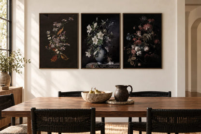 Three dark flower prints hang in a bright dining room by a window.