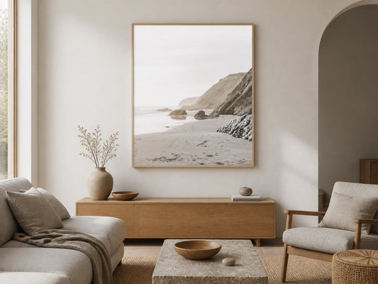 Neutral coastal cliff print above a pale-oak console in a warm white living room