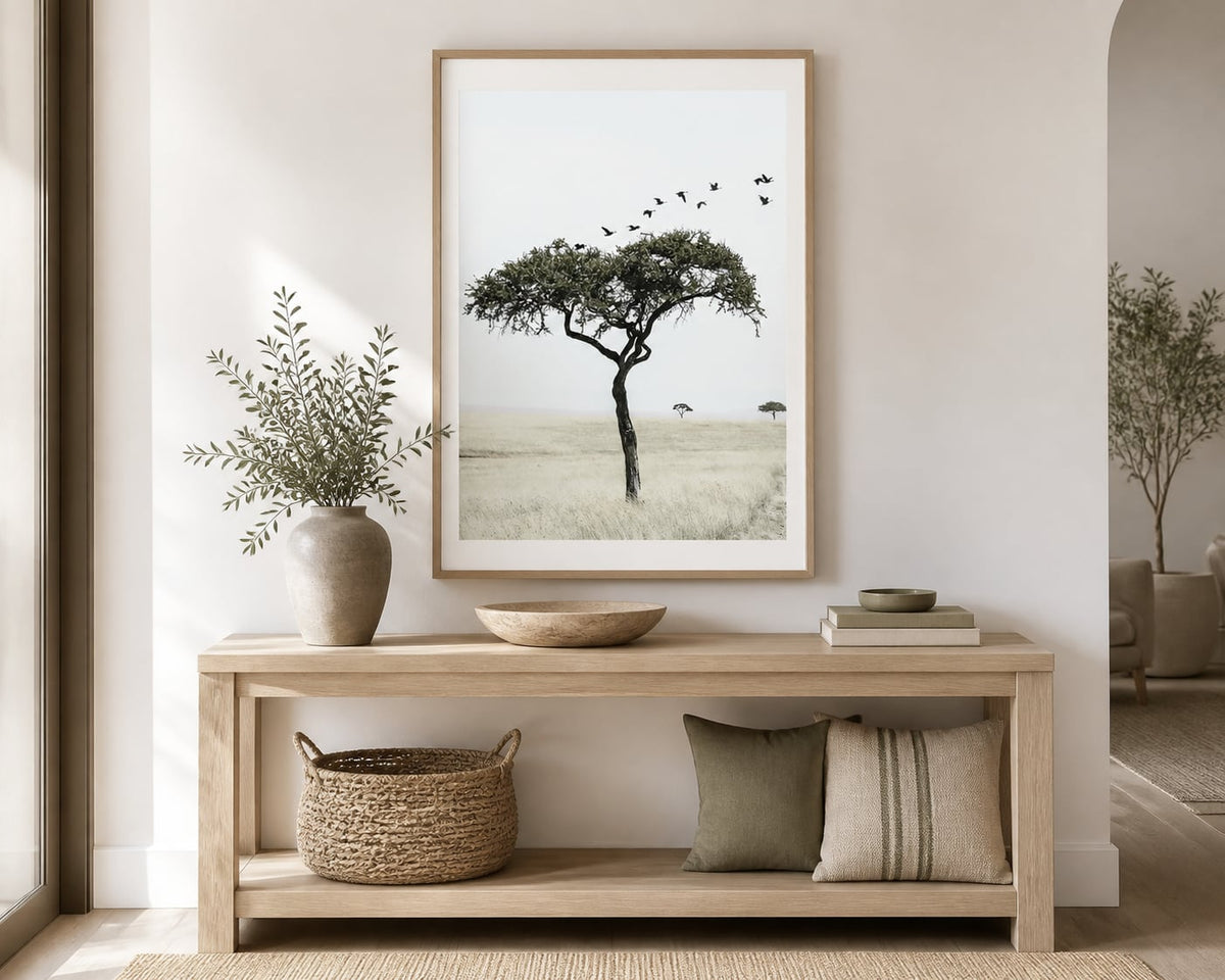 Lone tree and birds print above a pale-oak console in a warm ivory entryway