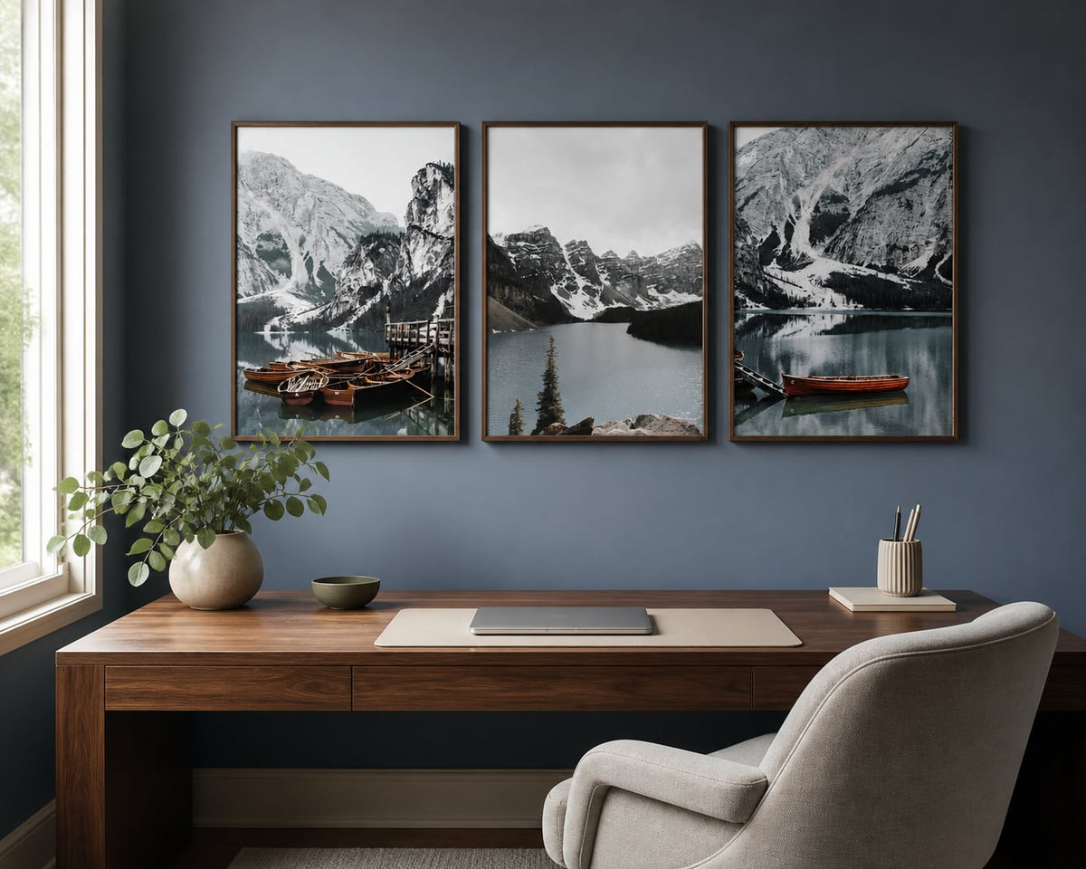 Mountain lake and boats triptych above a walnut desk on a blue-gray wall