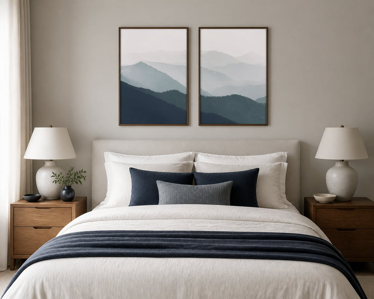 Misted mountain-ridges pair above an ivory bed with navy and blue-gray textiles