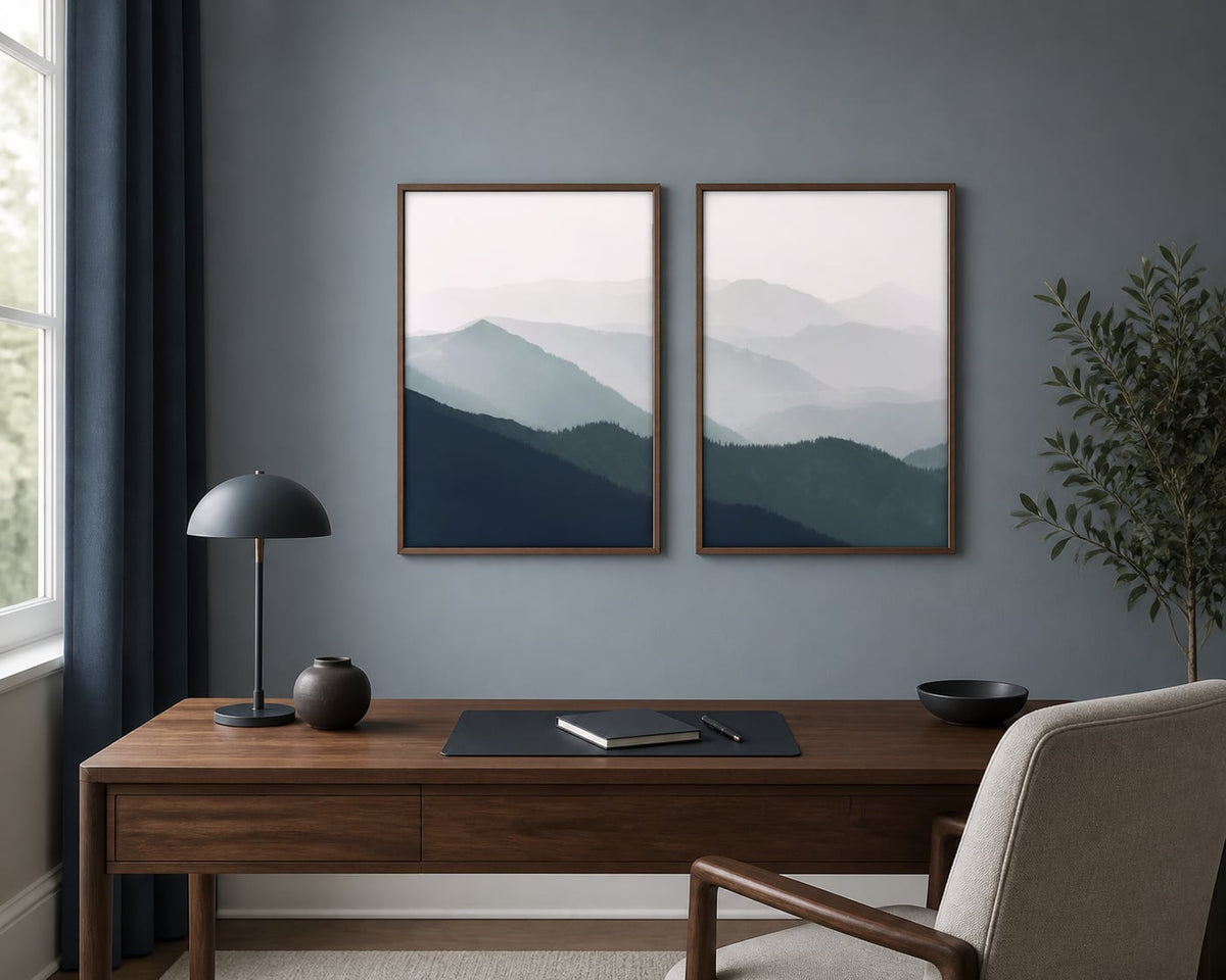 Misted mountain-ridges pair above a walnut desk on a blue-gray office wall