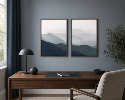 Misted mountain-ridges pair above a walnut desk on a blue-gray office wall