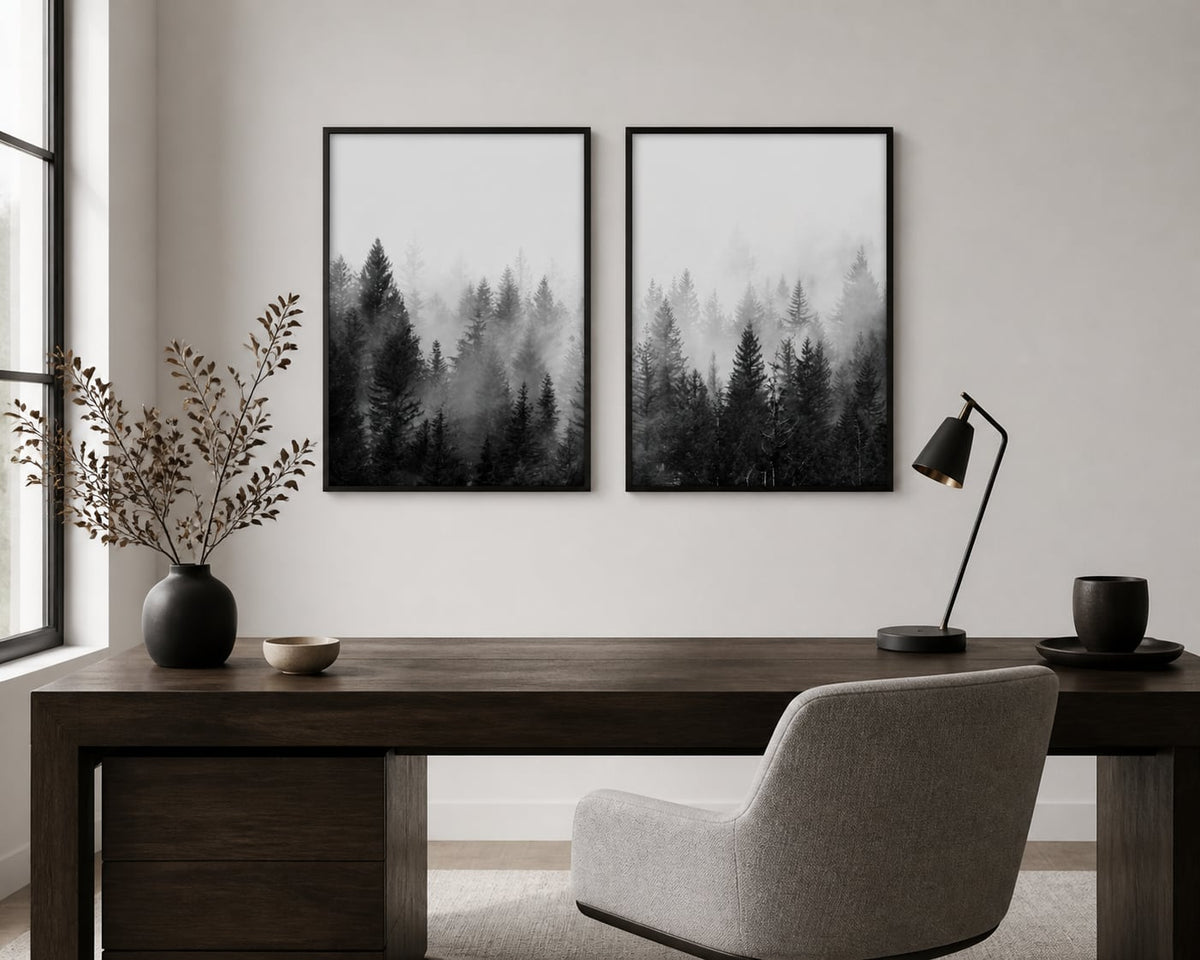 Monochrome misty-forest pair above a dark-walnut desk in a minimal office