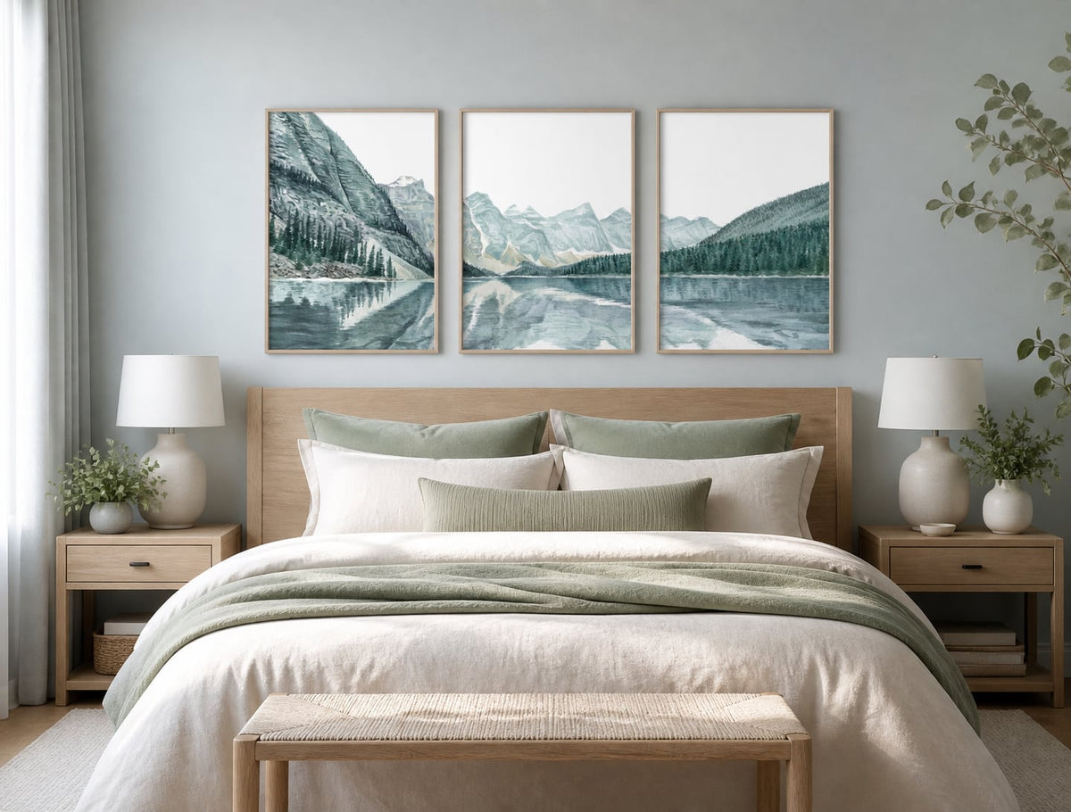 Pale mountain-lake triptych above an ivory bed with sage textiles