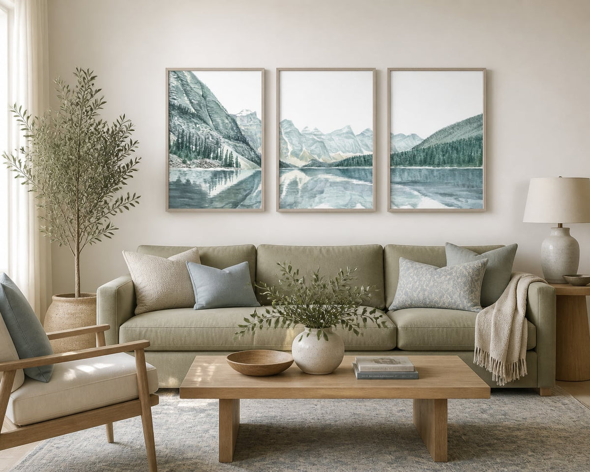 Pale mountain-lake triptych in a soft sage and pale-oak living room