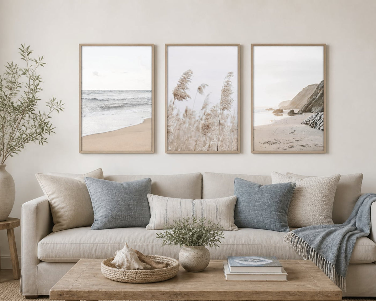 Neutral coastal triptych in a warm white living room with sand and blue-gray accents