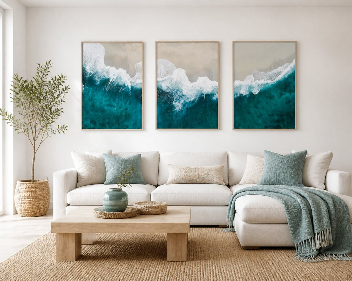 Turquoise shoreline triptych in a bright warm-white living room with pale oak