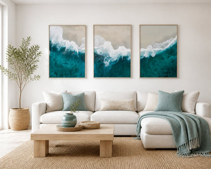 Turquoise shoreline triptych in a bright warm-white living room with pale oak