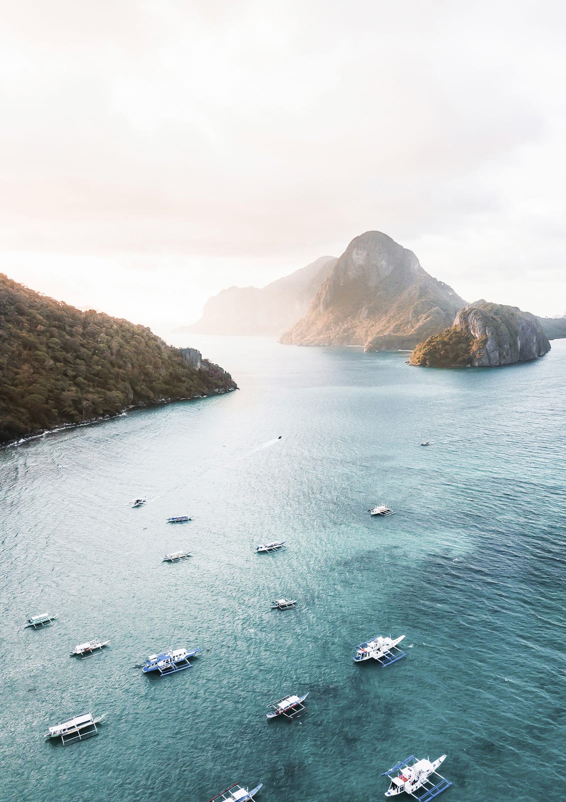 A small green island sits within broad turquoise and deep-blue water viewed from above