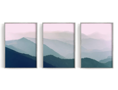 Three layered blue-green mountain panels beneath a pale pink horizon