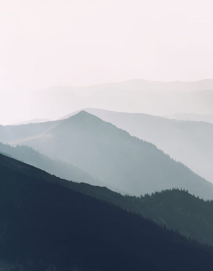 Layered blue-gray mountain ridges fading into pale mist