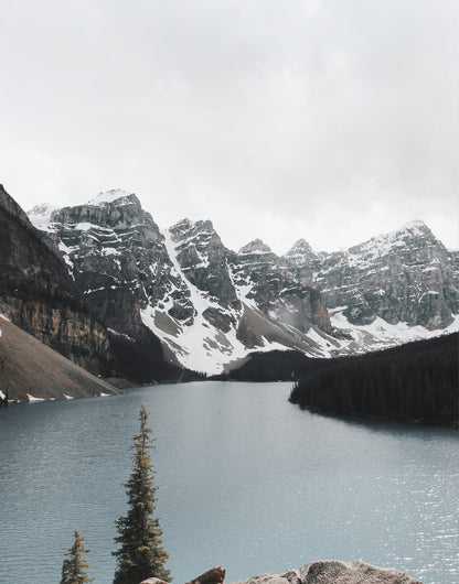 Mountain lake below snow-streaked peaks and a conifer shoreline