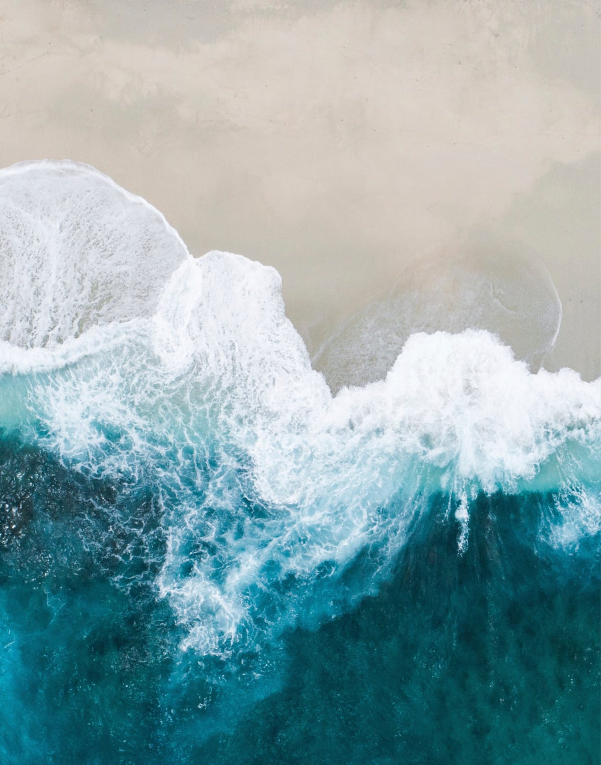 White surf breaking between turquoise water and sand