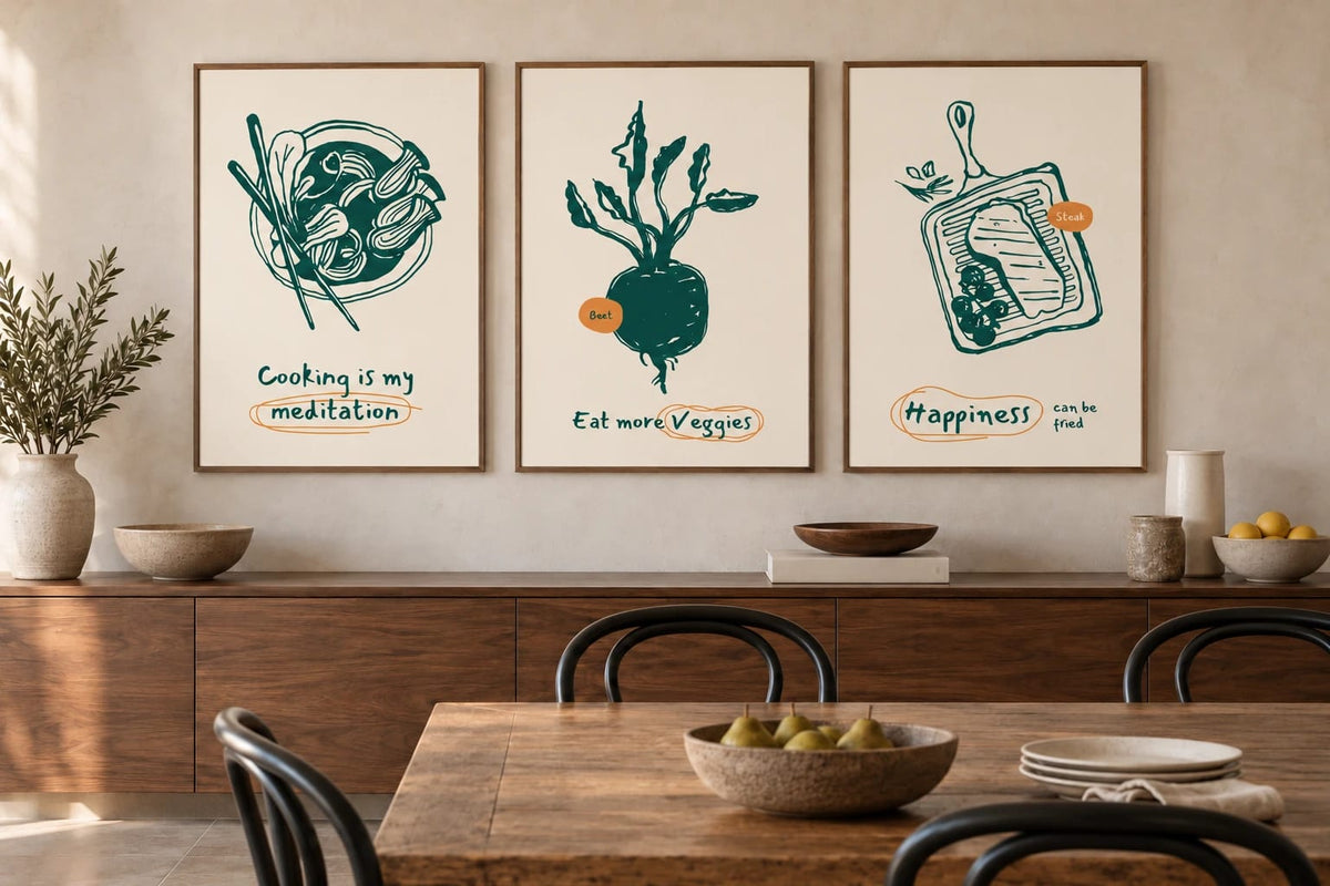 Three prints of foods, beet, and steak hang above a long wood cabinet in a neutral dining room.