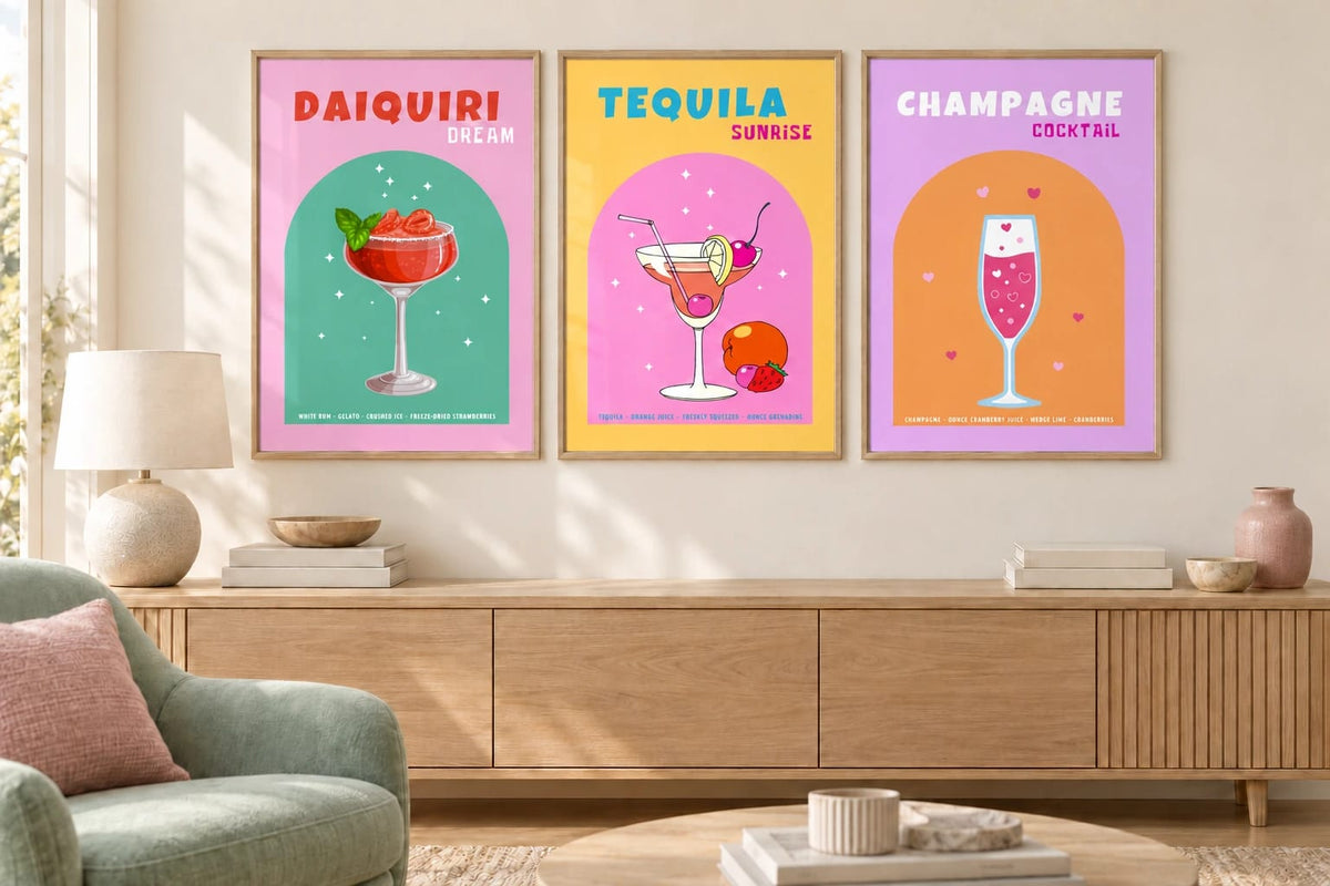 Three cocktail prints hang above a wood cabinet beside a chair.