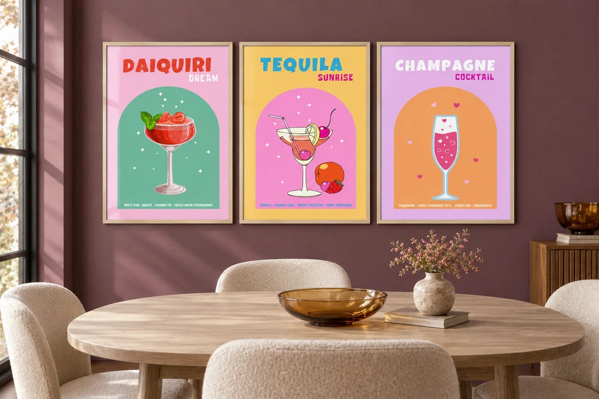 Three cocktail illustrations hang on a plum wall above a round dining table.