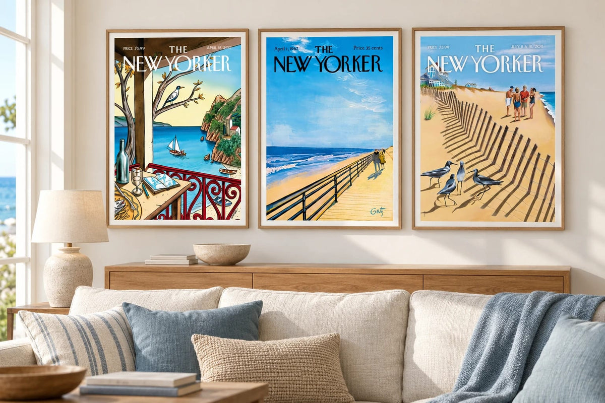 Three coastal prints hang above a sofa on a light living room wall.
