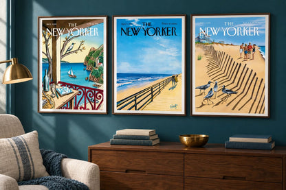 Three seaside scenes hang on a dark blue wall above a wood cabinet.