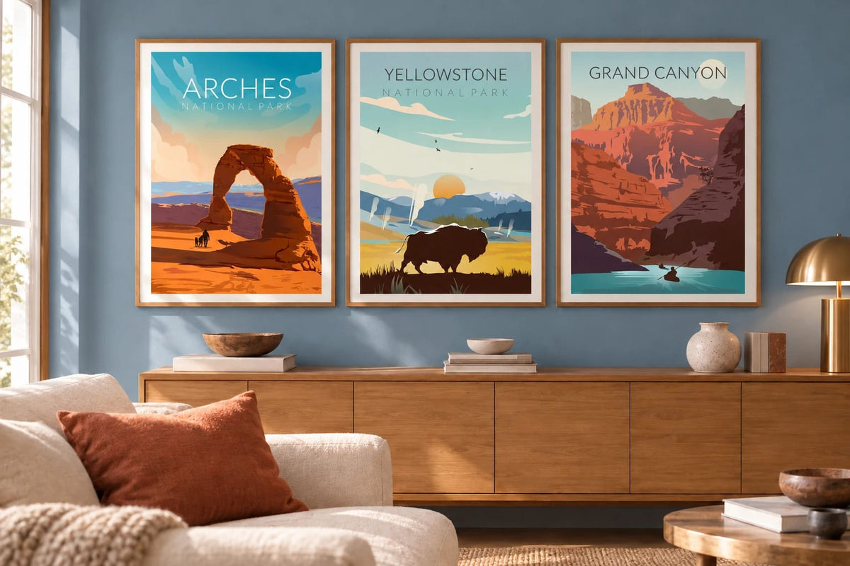 Three landscape prints hang above a cabinet on a dusty blue living room wall.