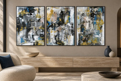 Abstract prints hang above a stone cabinet beside a light chair.