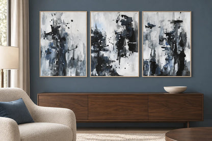 Black-gray prints with blue details hang against a dark blue-gray wall above a walnut cabinet.