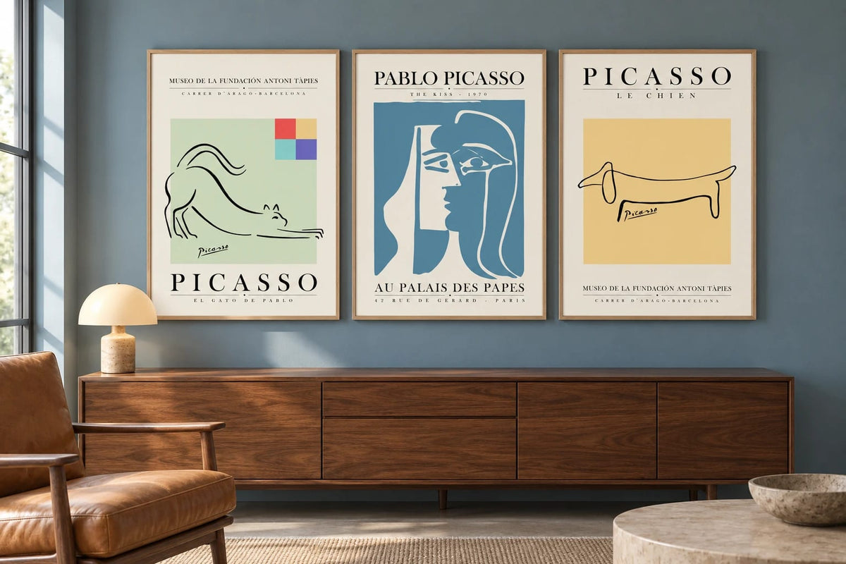 Graphic triptych above walnut furniture against a blue-gray wall.