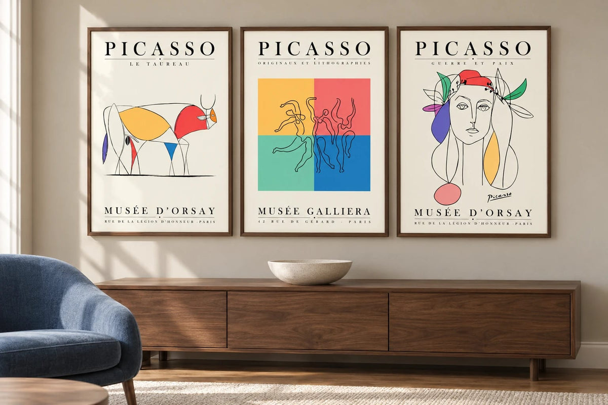 Colorful bull and figure prints above a sideboard near a blue chair.