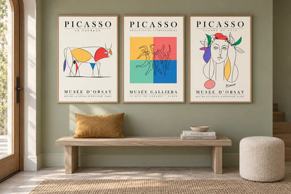 Three prints above a bench with a mustard cushion.