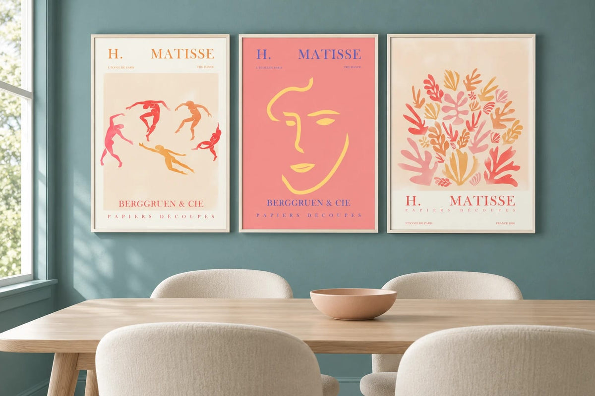 Abstract triptych above a dining table with light chairs.