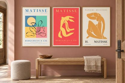 Abstract trio above a woven bench with a pale pouf.