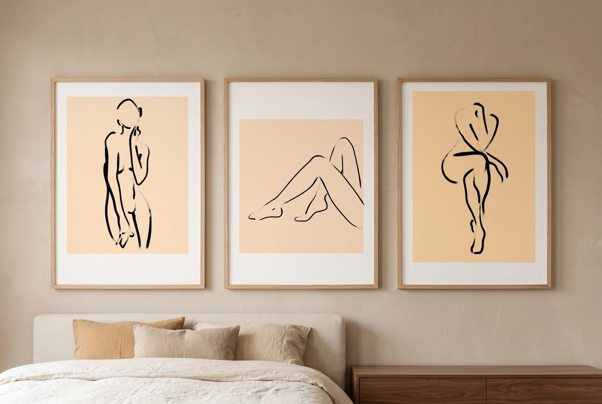 Figure prints with peach panels displayed above a bed.