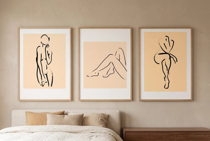 Figure prints with peach panels displayed above a bed.
