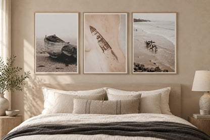 Three shore scenes above a bed in a beige bedroom.
