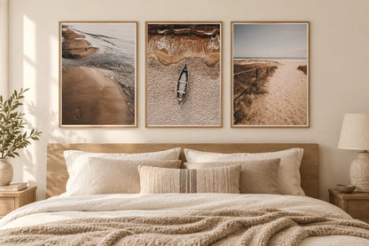 Beach prints above a bed in a beige bedroom.