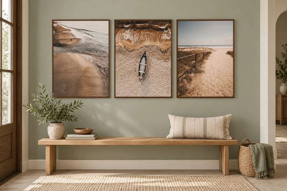 Three coastal prints above a bench in an olive entryway.