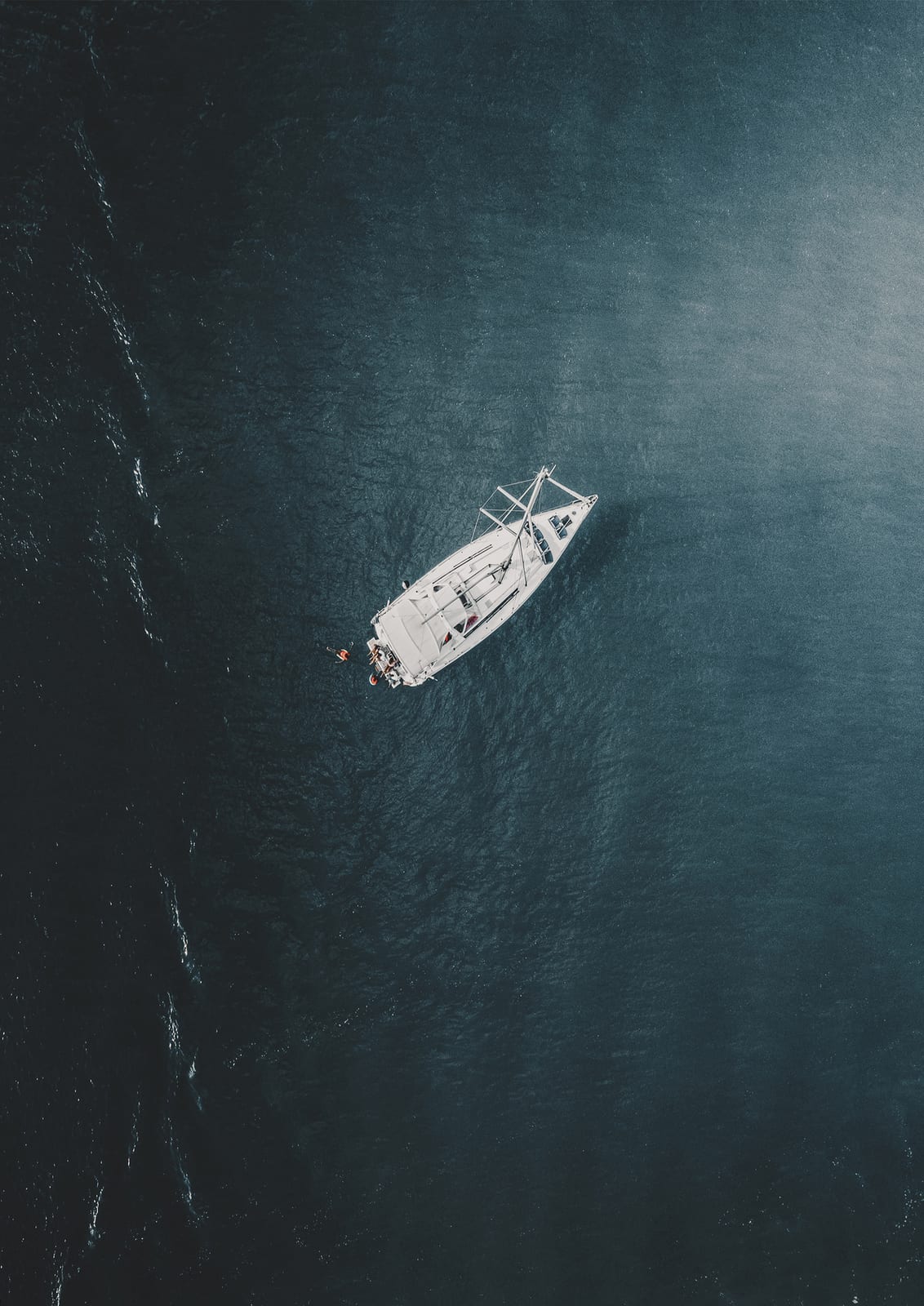 white sailboat on dark turquoise water.