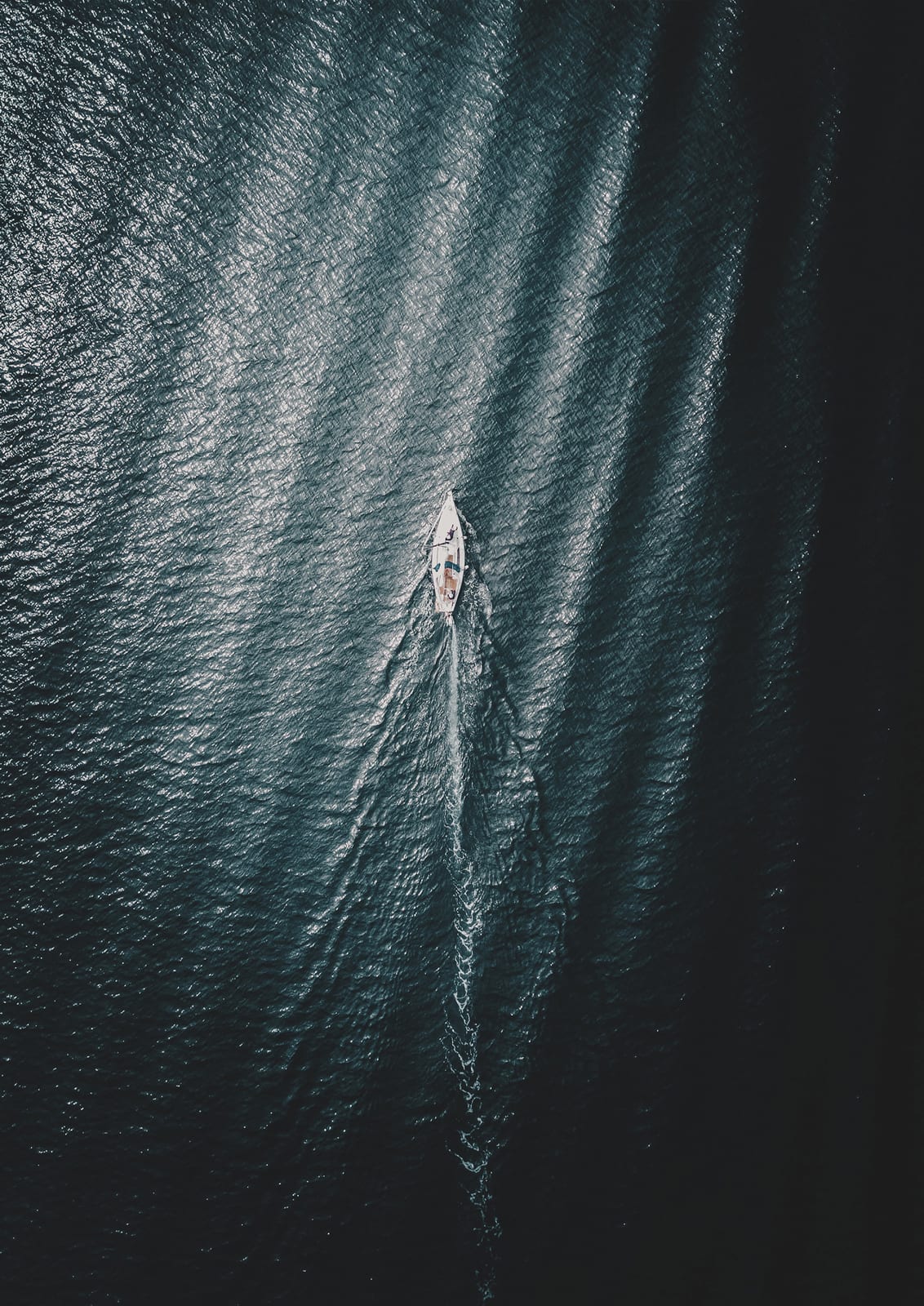 sailboat and wake on dark water.